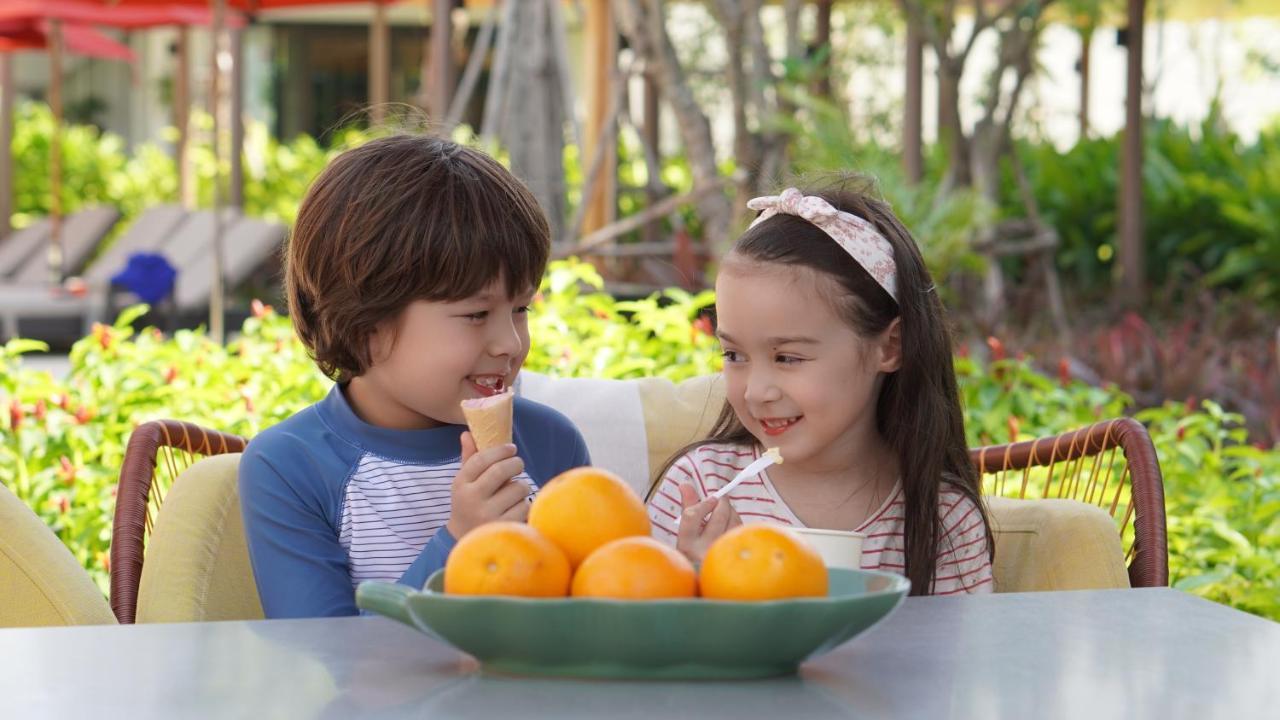 Amari Pattaya Hotel Exterior foto A boy and a girl eating fruit